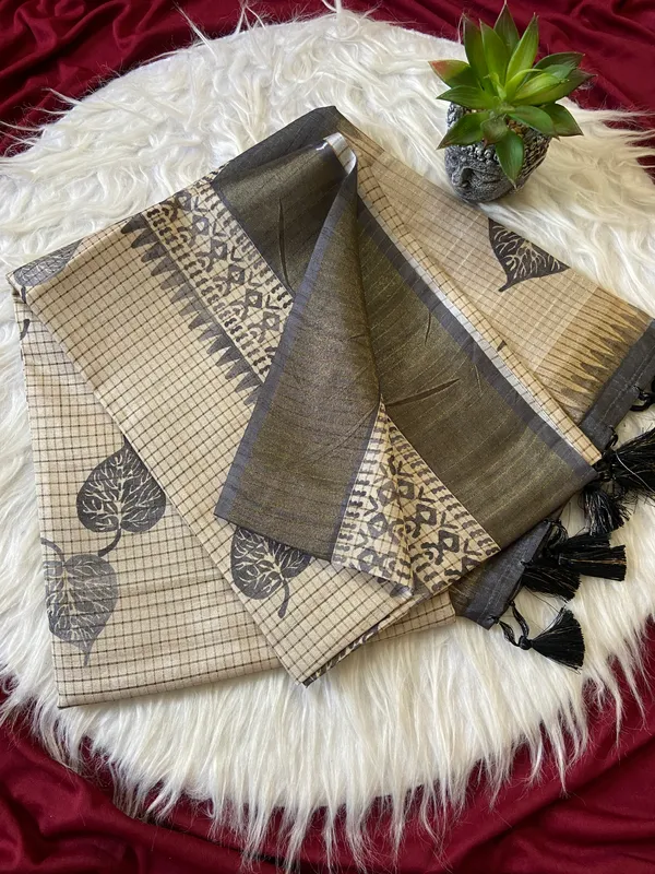 Soft_Tussar_Silk_sarees_with_Beautiful_Hand-Block_Inspired_Leaf_Digitel_Print:_The_primary_motif_consists_of_pipal_leaf_patterns_in_vibrant_shades_With_Temple_Border_The_serrated,_triangular_pattern_lining_the_is_a_classic_Indian_design_known_as_a_Temple_border_or_Temple_motif._This_is_a_staple_in_traditional_South_Indian_textiles_With_Attractive_Checks_Design_Saree_And_Digital_Print_Blouse_With_Tassels