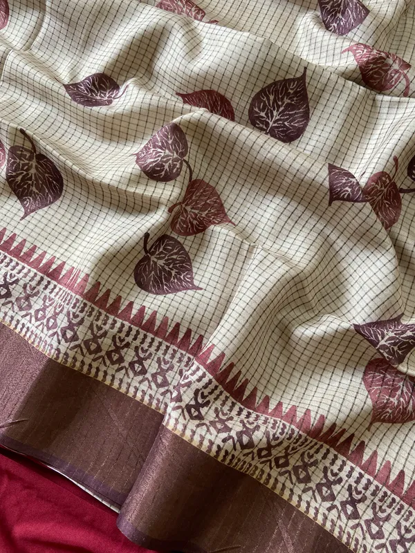 Soft_Tussar_Silk_sarees_with_Beautiful_Hand-Block_Inspired_Leaf_Digitel_Print:_The_primary_motif_consists_of_pipal_leaf_patterns_in_vibrant_shades_With_Temple_Border_The_serrated,_triangular_pattern_lining_the_is_a_classic_Indian_design_known_as_a_Temple_border_or_Temple_motif._This_is_a_staple_in_traditional_South_Indian_textiles_With_Attractive_Checks_Design_Saree_And_Digital_Print_Blouse_With_Tassels