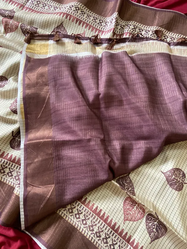 Soft_Tussar_Silk_sarees_with_Beautiful_Hand-Block_Inspired_Leaf_Digitel_Print:_The_primary_motif_consists_of_pipal_leaf_patterns_in_vibrant_shades_With_Temple_Border_The_serrated,_triangular_pattern_lining_the_is_a_classic_Indian_design_known_as_a_Temple_border_or_Temple_motif._This_is_a_staple_in_traditional_South_Indian_textiles_With_Attractive_Checks_Design_Saree_And_Digital_Print_Blouse_With_Tassels