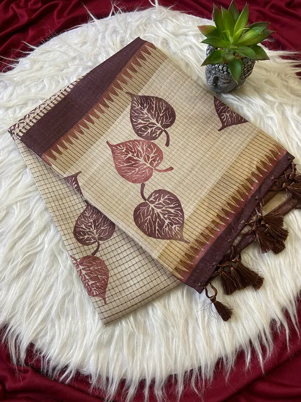Soft_Tussar_Silk_sarees_with_Beautiful_Hand-Block_Inspired_Leaf_Digitel_Print:_The_primary_motif_consists_of_pipal_leaf_patterns_in_vibrant_shades_With_Temple_Border_The_serrated,_triangular_pattern_lining_the_is_a_classic_Indian_design_known_as_a_Temple_border_or_Temple_motif._This_is_a_staple_in_traditional_South_Indian_textiles_With_Attractive_Checks_Design_Saree_And_Digital_Print_Blouse_With_Tassels