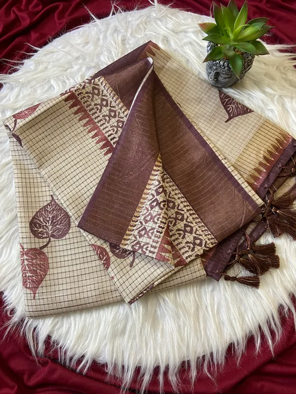 Soft_Tussar_Silk_sarees_with_Beautiful_Hand-Block_Inspired_Leaf_Digitel_Print:_The_primary_motif_consists_of_pipal_leaf_patterns_in_vibrant_shades_With_Temple_Border_The_serrated,_triangular_pattern_lining_the_is_a_classic_Indian_design_known_as_a_Temple_border_or_Temple_motif._This_is_a_staple_in_traditional_South_Indian_textiles_With_Attractive_Checks_Design_Saree_And_Digital_Print_Blouse_With_Tassels