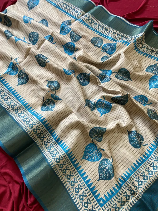 Soft_Tussar_Silk_sarees_with_Beautiful_Hand-Block_Inspired_Leaf_Digitel_Print:_The_primary_motif_consists_of_pipal_leaf_patterns_in_vibrant_shades_With_Temple_Border_The_serrated,_triangular_pattern_lining_the_is_a_classic_Indian_design_known_as_a_Temple_border_or_Temple_motif._This_is_a_staple_in_traditional_South_Indian_textiles_With_Attractive_Checks_Design_Saree_And_Digital_Print_Blouse_With_Tassels