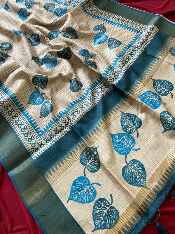 Soft_Tussar_Silk_sarees_with_Beautiful_Hand-Block_Inspired_Leaf_Digitel_Print:_The_primary_motif_consists_of_pipal_leaf_patterns_in_vibrant_shades_With_Temple_Border_The_serrated,_triangular_pattern_lining_the_is_a_classic_Indian_design_known_as_a_Temple_border_or_Temple_motif._This_is_a_staple_in_traditional_South_Indian_textiles_With_Attractive_Checks_Design_Saree_And_Digital_Print_Blouse_With_Tassels