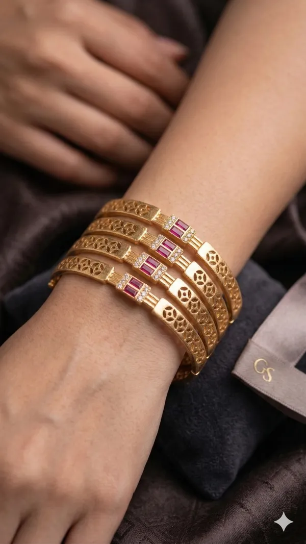 Add_A_Touch_Of_Royal_Elegance_To_Your_Jewelry_Collection_with_These_Beautifully_Crafted_Micro_Gold_Plated_And_&_Ruby_Stone_Studded_Bangles._Designed_with_Intricate_Floral_Cutwork_Detailing,_These_Bangles_Feature_A_Stunning_Centerpiece_Adorned_with_Sparkling_American_Diamonds_And_Rich_Ruby-Colored_Stones_That_Enhance_Their_Luxurious_Appeal.