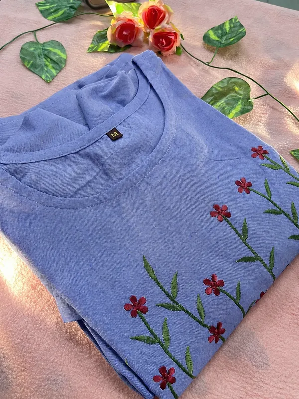 This_is_a_blue_knee-length_A-line_dress_with_short_sleeves_and_a_round_neckline._The_bodice_features_colorful_floral_embroidery._It_is_paired_with_a_beige_shoulder_bag_and_beige_sandals._This_style_is_suitable_for_casual_outings,_brunches,_or_daytime_events.