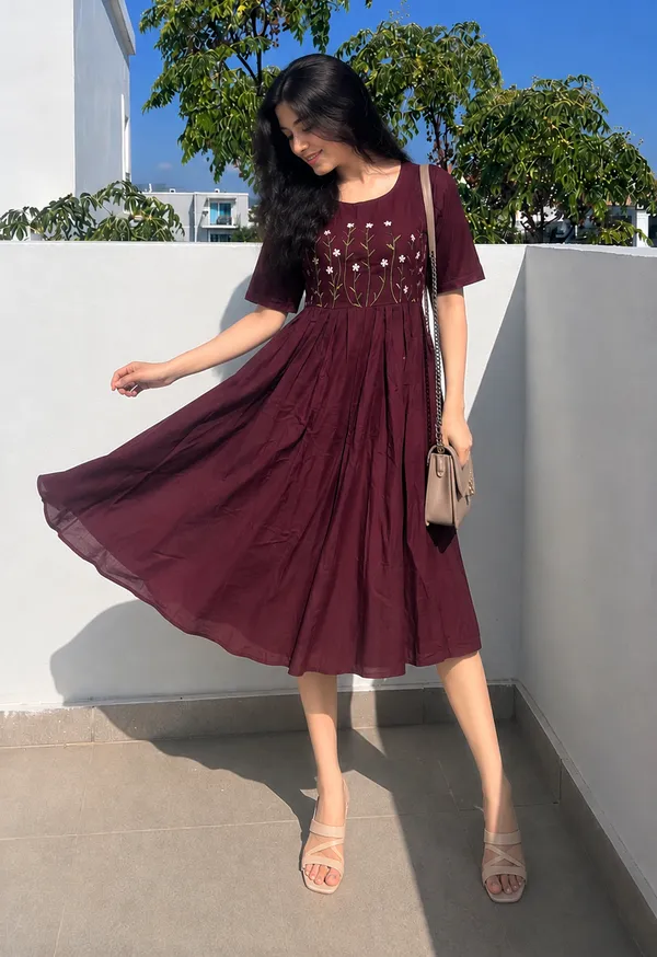 This_is_a_purple_knee-length_A-line_dress_with_short_sleeves_and_a_round_neckline._The_bodice_features_colorful_floral_embroidery._It_is_paired_with_a_beige_shoulder_bag_and_beige_sandals._This_style_is_suitable_for_casual_outings,_brunches,_or_daytime_events.