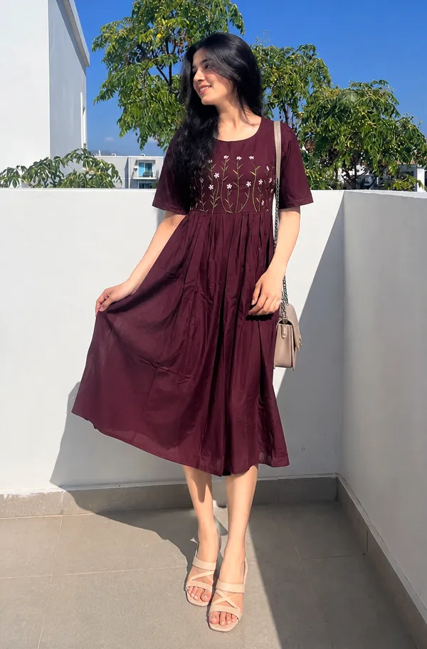 This_is_a_purple_knee-length_A-line_dress_with_short_sleeves_and_a_round_neckline._The_bodice_features_colorful_floral_embroidery._It_is_paired_with_a_beige_shoulder_bag_and_beige_sandals._This_style_is_suitable_for_casual_outings,_brunches,_or_daytime_events.