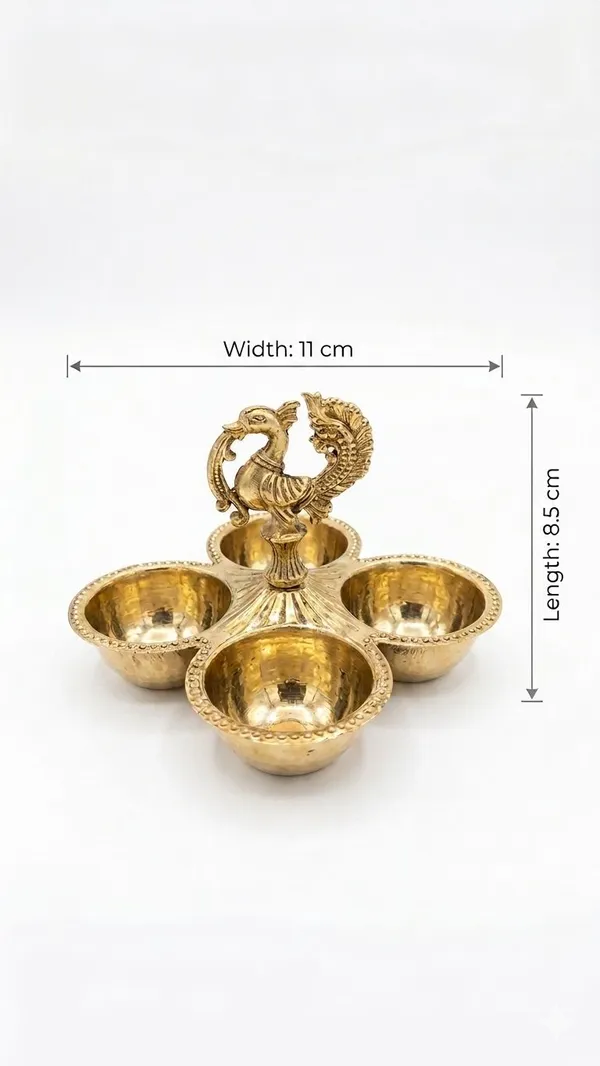 Shubh_Aura_Pure_Brass_hand_crafted_pooja_essential_holder._It_can_hold_Chawal,_Haldi,_Kumkum,_Mishri_all_kind_of_pooja_essential_together,_It�s_a_very_practical_addition_to_any_pooja_routine._Its_has_4_carved_bowls_and_peacock_carving_at_top_which_create_a_cohesive_and_harmonious_look_to_pooja_space,_width_&_length_is_11cm_&_height_8.5cm