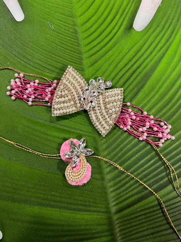 Couple_Rakhi_with_bow_on_the_center_for_bhabhi_bracelet_with_pink_coloured_tubes_hangings_on_the_sides_with_thread_for_tying