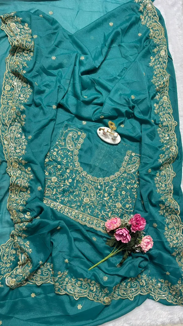 Stunning_Teal_Green_Designer_Saree_Step_into_the_spotlight_with_this_sophisticated_teal_green_saree._It_features_a_rich,_heavy_zari_embroidery_border_with_a_beautiful_scalloped_edge_and_delicate_paisley_motifs._The_saree_is_adorned_with_elegant_buttis_throughout_and_comes_with_a_matching,_heavily_embroidered_designer_blouse_piece_to_complete_your_festive_look