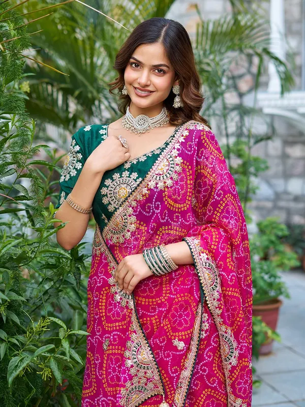 Pink_Bandhani_Saree_With_Heavy_Embellished_Border_And_Green_Embroidered_Blouse
