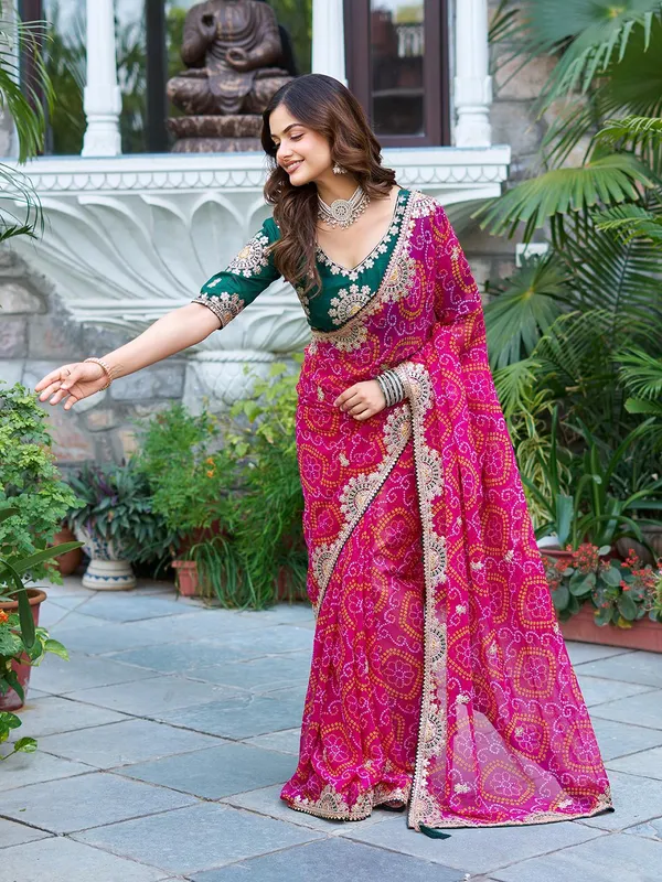 Pink_Bandhani_Saree_With_Heavy_Embellished_Border_And_Green_Embroidered_Blouse