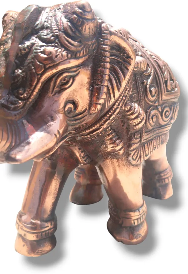 This_is_a_copper‑finished_decorative_statue_of_an_elephant_with_intricate_engraved_patterns_on_its_body,_head,_and_legs._The_craftsmanship_shows_detailed_filigree_work_and_an_antique,_regal_appearance,_making_it_a_stylish_décor_piece_for_display_or_gifting_-_9_INCH