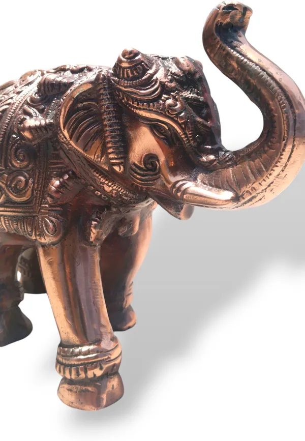 This_is_a_copper‑finished_decorative_statue_of_an_elephant_with_intricate_engraved_patterns_on_its_body,_head,_and_legs._The_craftsmanship_shows_detailed_filigree_work_and_an_antique,_regal_appearance,_making_it_a_stylish_décor_piece_for_display_or_gifting_-_9_INCH