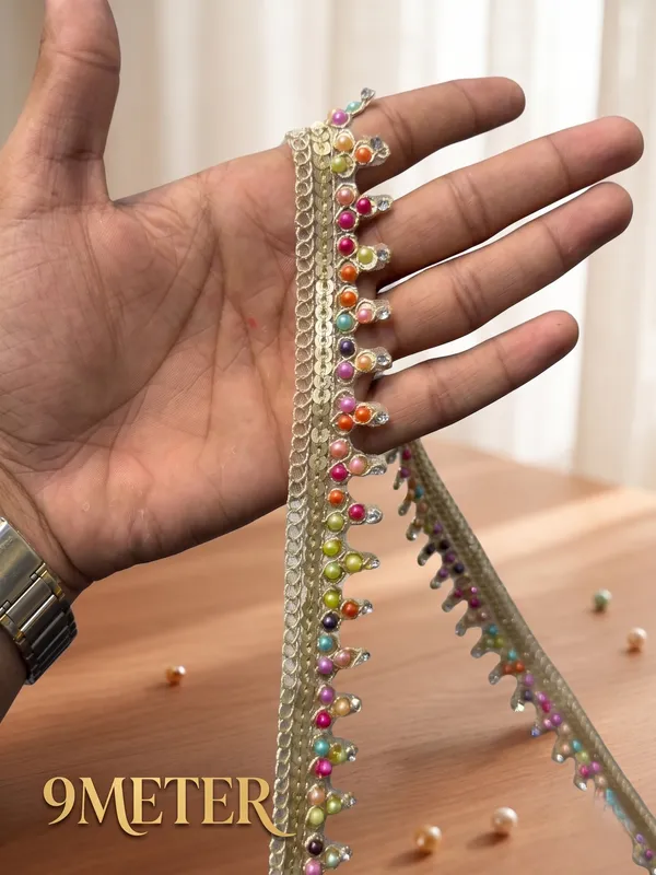Bring_a_vibrant,_festive_burst_of_color_to_your_ethnic_wear_with_this_stunning_Multicolored_Bead_and_Sequin_Lace_Trim._Featuring_a_glistening_gold_woven_mesh_base_detailed_with_shimmering_sequins_and_hanging_loops_adorned_with_multi-colored_pearls_and_tiny_crystal_stones,_this_designer_border_adds_a_lively_and_artistic_touch_to_any_garment.