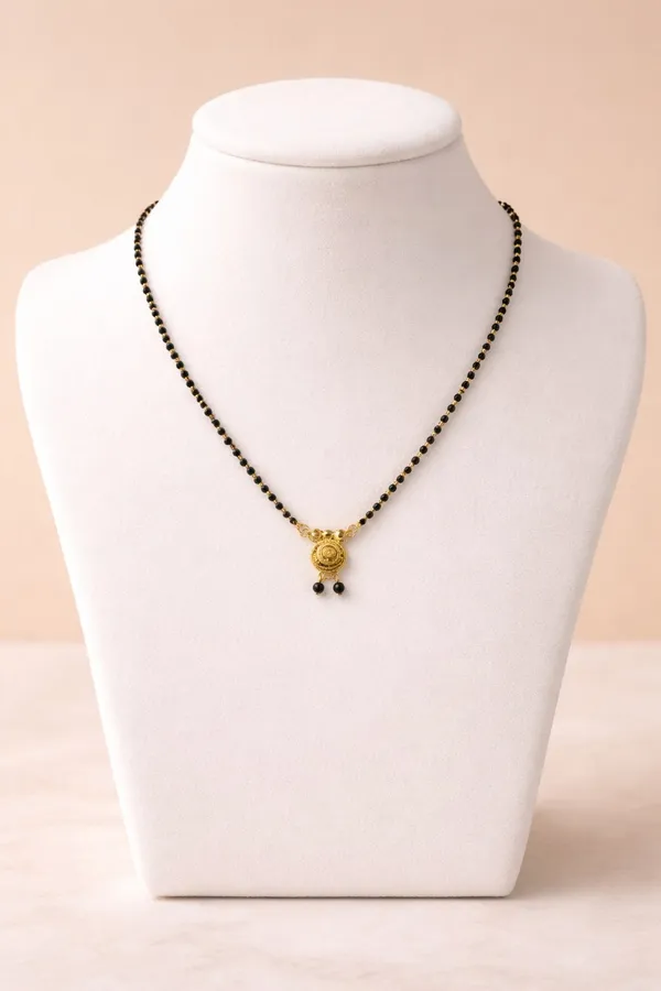 Elegant_single-chain_mangalsutra_with_black_beads_and_a_gold-toned_circular_pendant