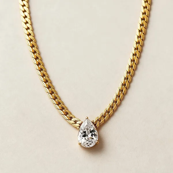 Classic_Multi_Prong_Gold_Bezel_Featuring_A_Teardrop_Gem_Suspended_Directly_From_A_Bold,_Textured_Flat_Figaro_Style_Chain_(Gold)