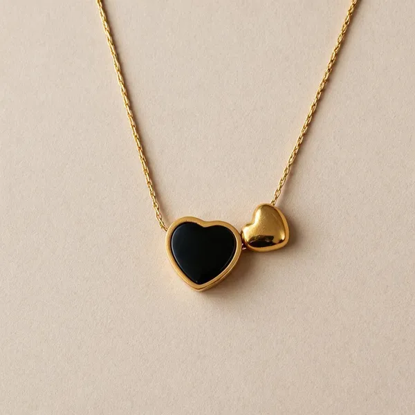 Asymmetrical_Dual_Heart_Motif_Romantic_Pendant_Necklace_Featuring_A_Central_Heart_Frame_Set_With_Sleek_Black_Enamel_Inlay_Sitting_Beside_A_Charming,_Mini_Solid_Puffed_Gold_Heart_Suspended_From_A_Delicate_Wheat_Chain_(Gold)