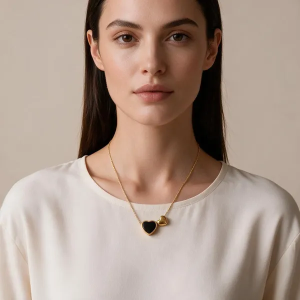 Asymmetrical_Dual_Heart_Motif_Romantic_Pendant_Necklace_Featuring_A_Central_Heart_Frame_Set_With_Sleek_Black_Enamel_Inlay_Sitting_Beside_A_Charming,_Mini_Solid_Puffed_Gold_Heart_Suspended_From_A_Delicate_Wheat_Chain_(Gold)