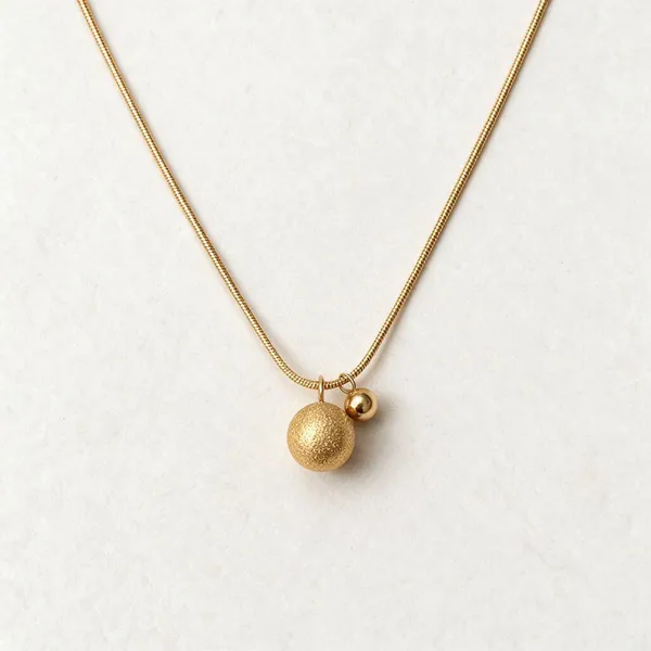 Dynamic_Pendant_Necklace_Pairs_A_Larger,_Sparkling_Frosted_Textured_Sphere_Alongside_A_Smaller,_High_Shine_Polished_Gold_Bead_Charm_(Gold)