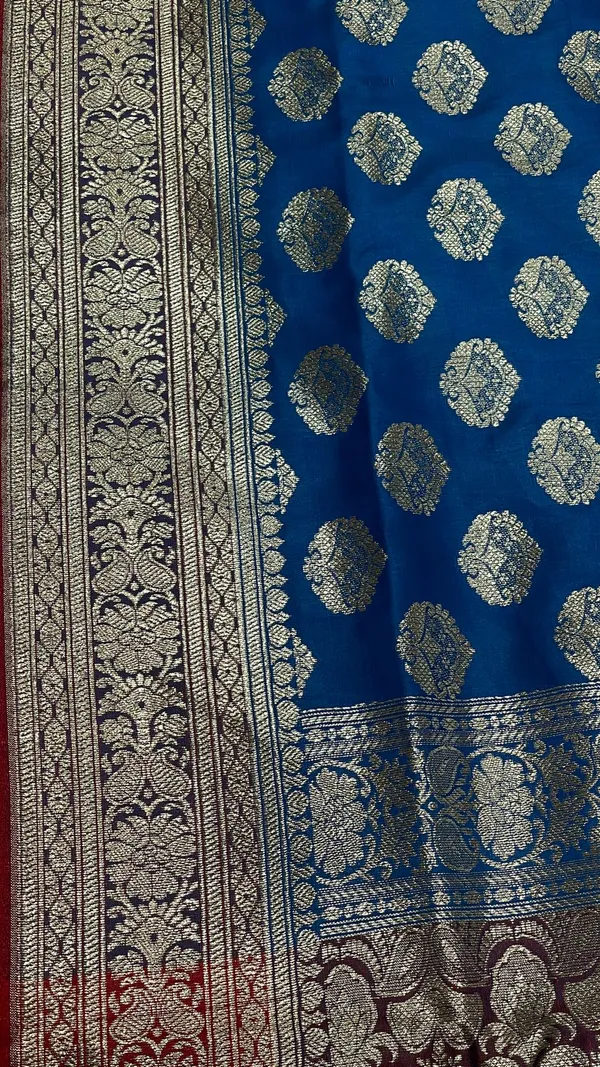 Humairah_Presents_Blue_Satin_Silk_Silver_Zari_Floral_Boota_and_Contrast_Red_Zari_Border_and_Heavy_Silver_Zari_Floral_Anchal_Banarasi_Saree_with_Red_Blouse